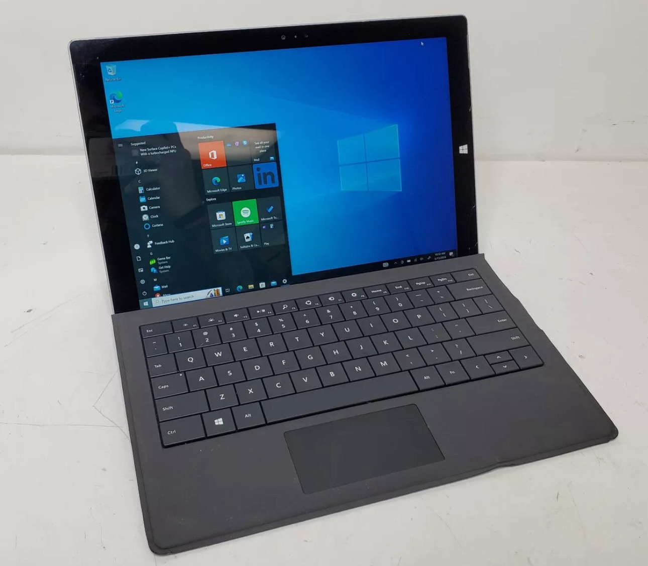 Microsoft Surface Pro 3 tablet laptop powered on with Windows 10 desktop and attached black Type Cover keyboard.
